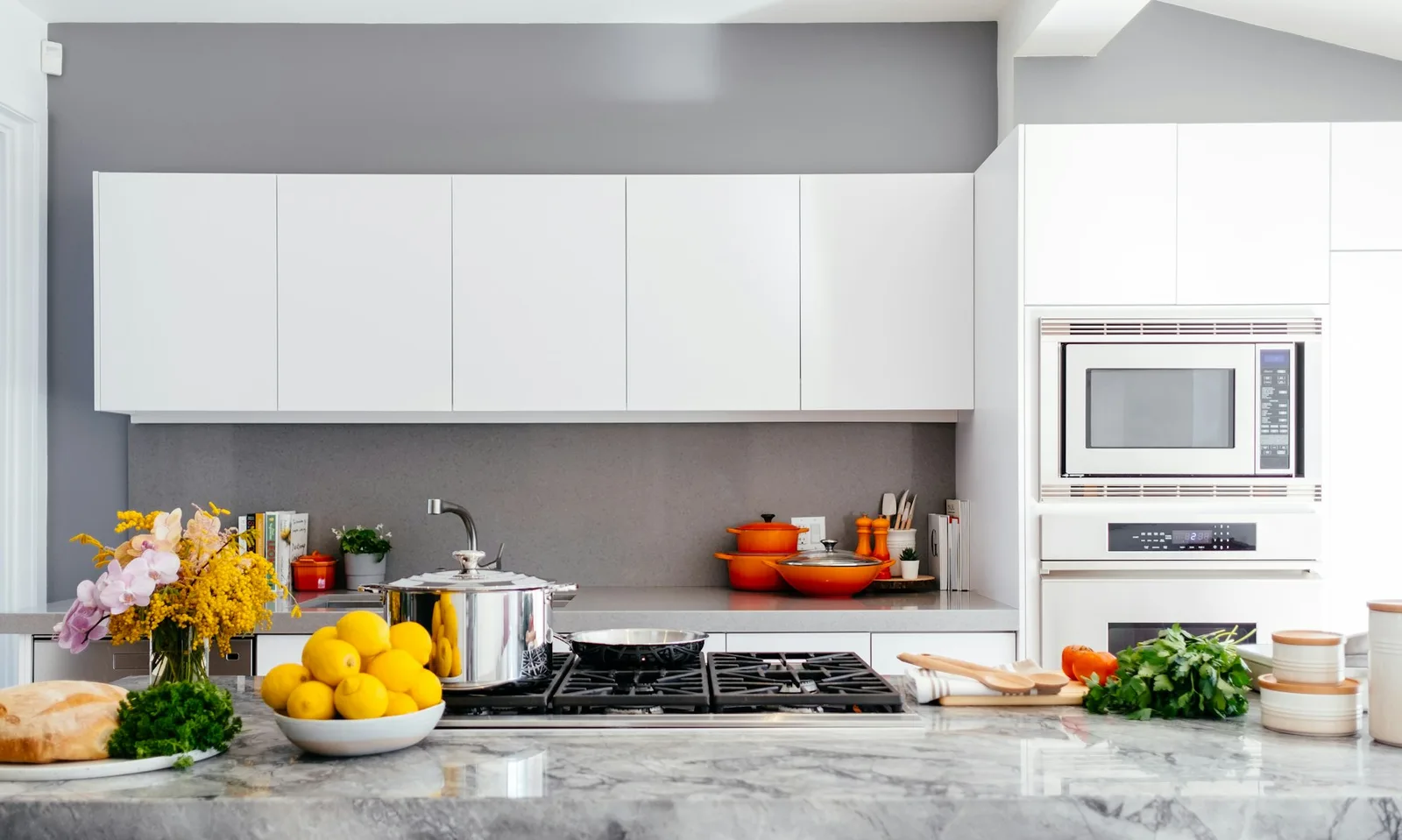 Bright kitchen with pale cabinetry, fresh produce, and a broad stone island
